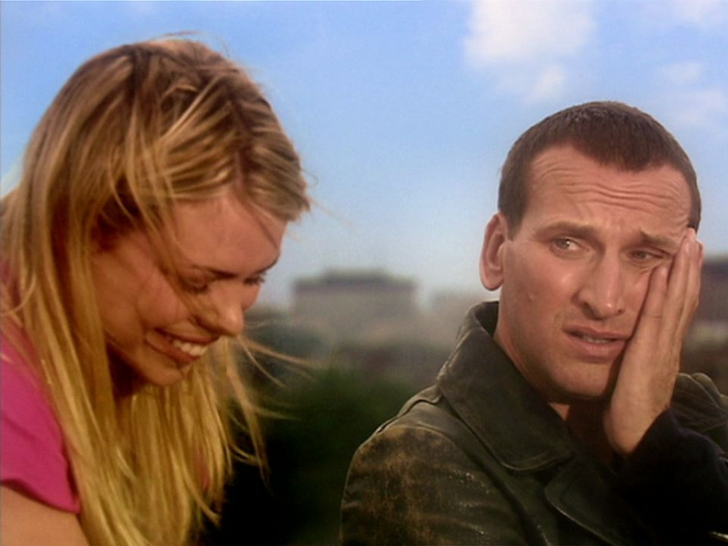 Rose (Billie Piper) is laughing and the Ninth Doctor (Christopher Eccleston) is holding his face