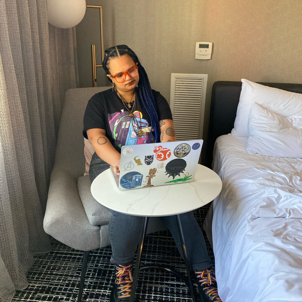 Talia working on their laptop in a hotel room