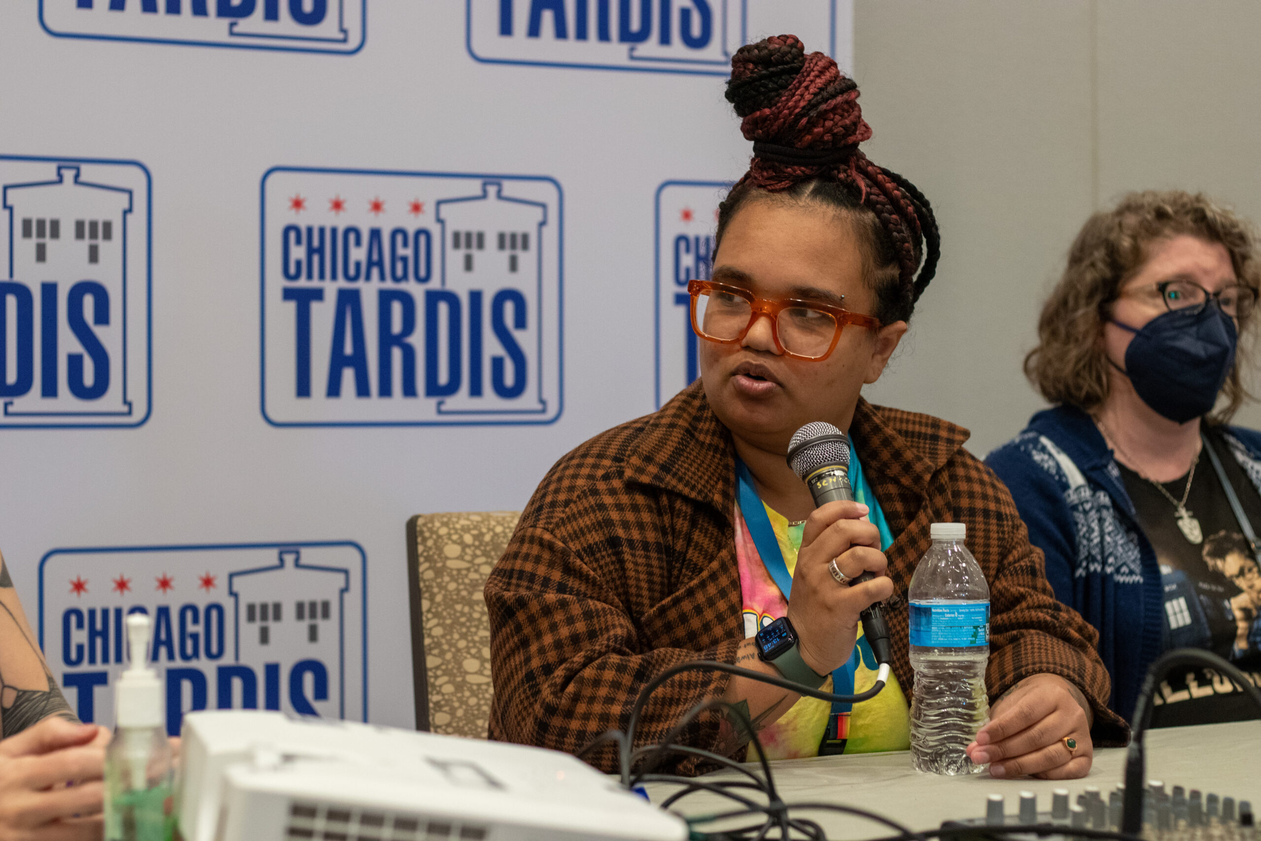 Talia speaking into a microphone at the Chicago Tardis "History of Studying Doctor Who" panel in November 2023