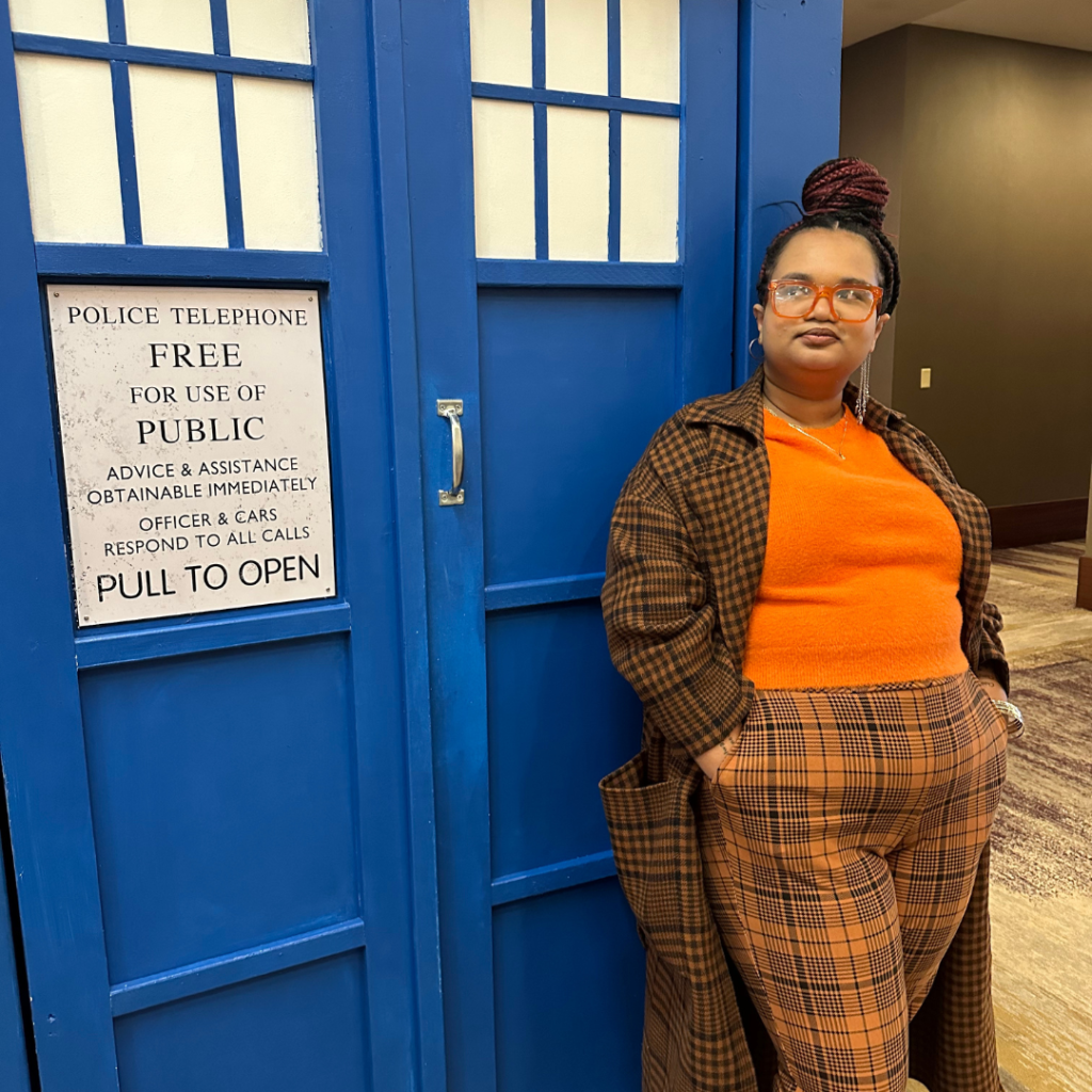 Talia in Fifteenth Doctor cosplay standing outside a Tardis